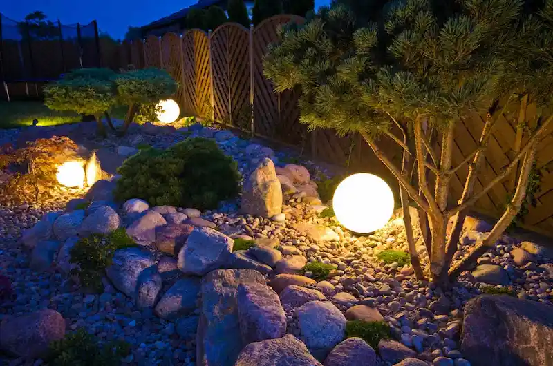 Khu fire pit bằng đá giữa sân vườn, ghế gỗ xung quanh, ánh sáng đêm ấm cúng. (Nguồn ảnh: Internet)